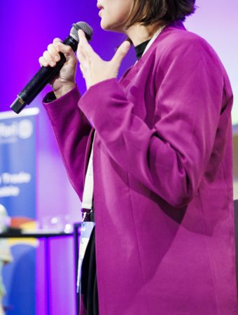 A women talking in a mic on a stage