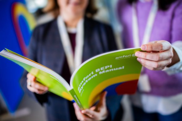 two persons looking at the amfori system manuel printed version