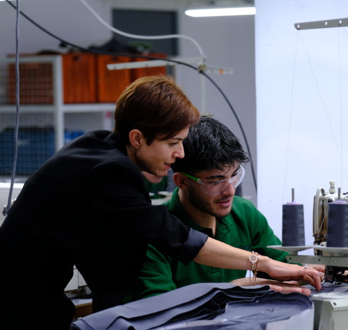 two persons talking next to knitting machine in a factory