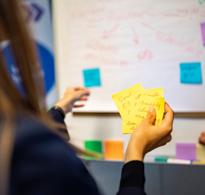 a person sticking sticky notes on a flipchart