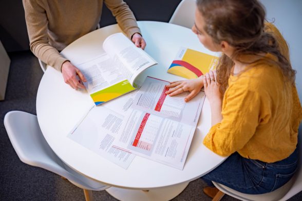 two persons looking at brochures on a table