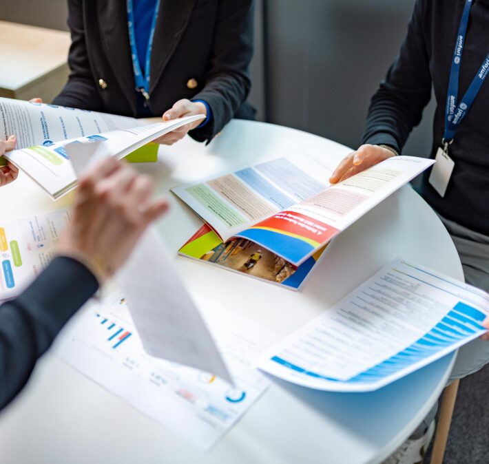 Three people around a table covered with documents
