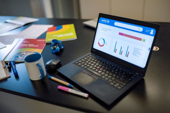 a laptop with dashboards on the screen and printed documents on the side